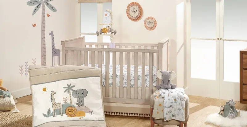 A soft nursery with a wooden crib, safari-themed bedding and wall decor, a mobile, and a plush elephant.